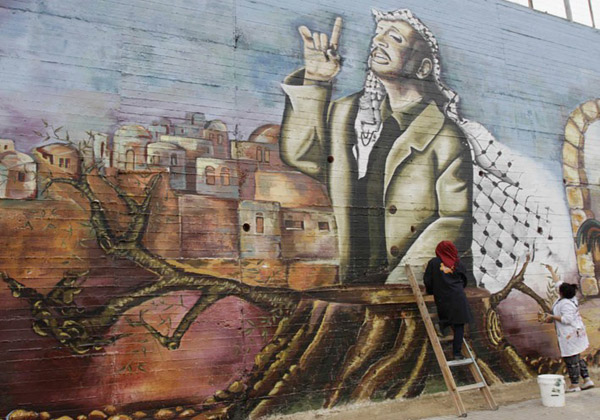 دانشجویان فلسطینی در حال کشیدن یک نقاشی دیواری از عرفات