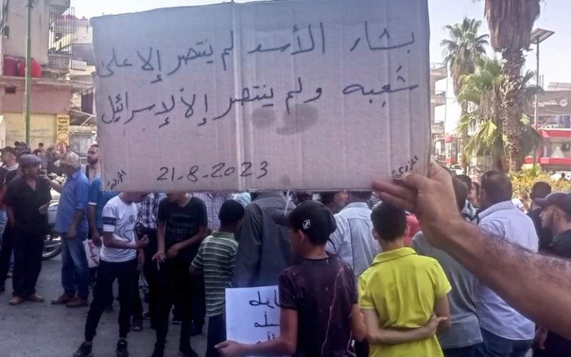 تظاهرات اعتراضی در سویدا در روز دوشنبه . روی پلاکارد نوشته است «بشار الاسد تنها بر ملت خود پیروز شد و نتوانست اسرائیل را شکست دهد.»