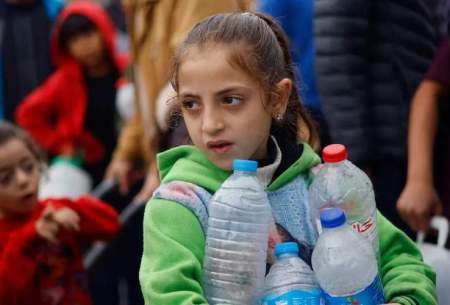 کودک غزه‌ای در حال حمل بطری‌های آب (رویترز)
